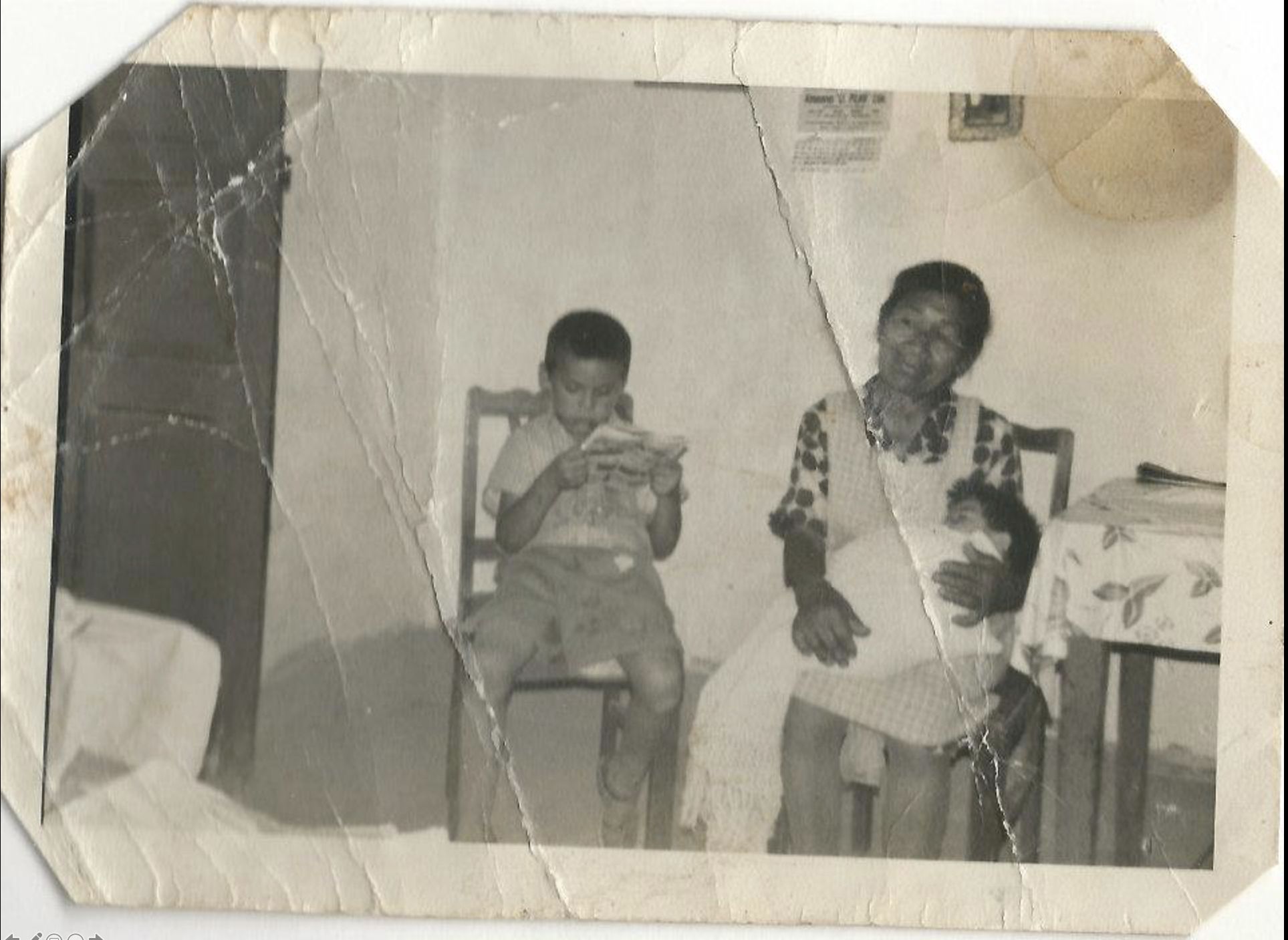 7-year-old Alfredo sitting on a chair, reading. Next to him is his his great-aunt holding her grandchild.