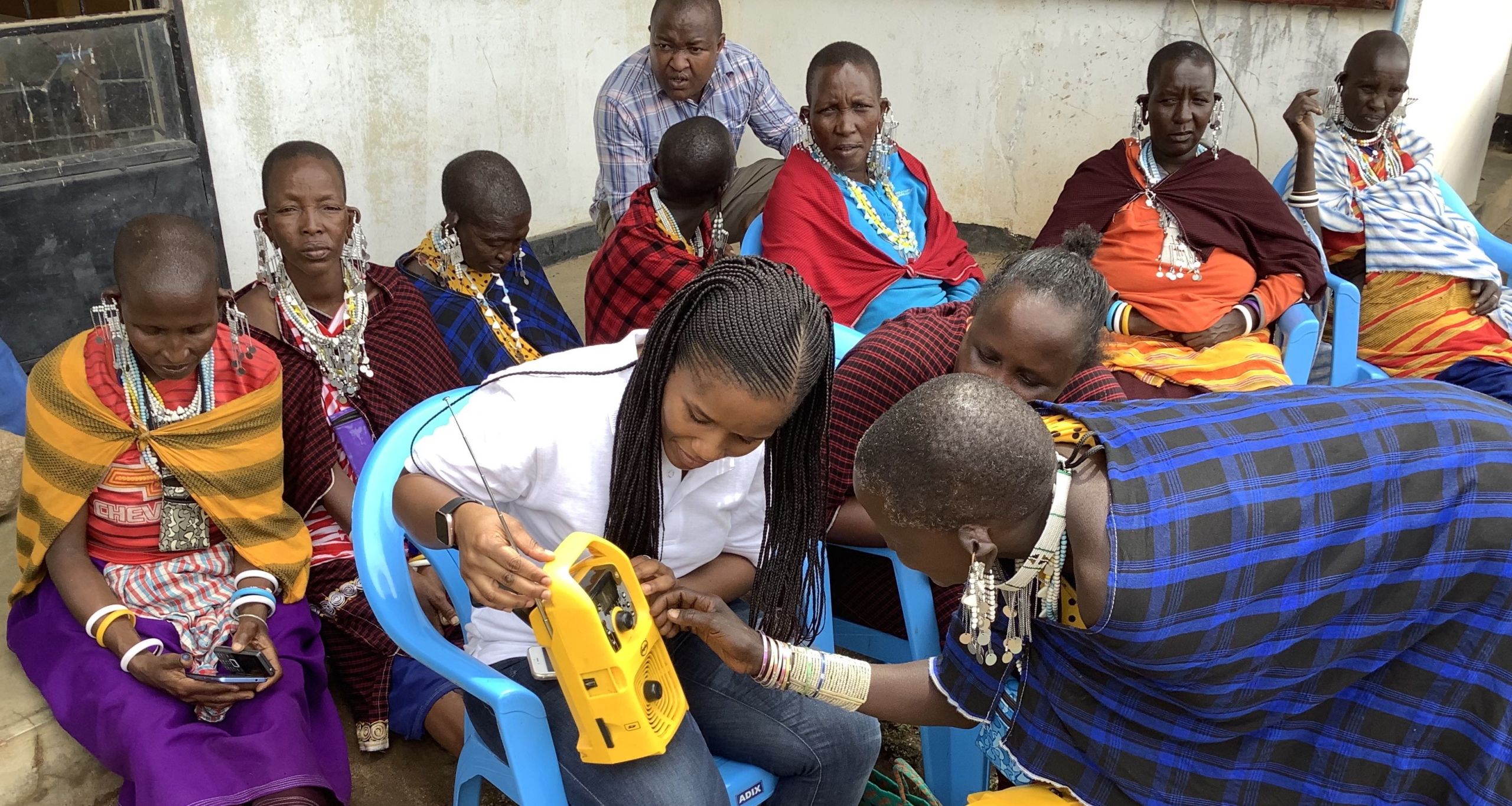A leader of a female community listening group in Tanzania demonstrates to climate expert Jacqueline Tesha how to operate a solar powered MP3 radio.
